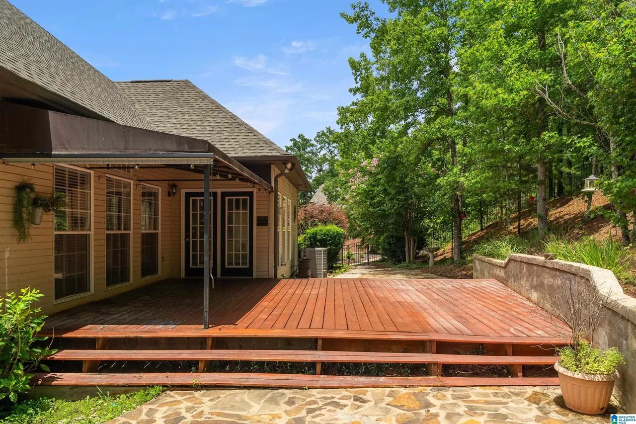 Wide wood deck and stone patio at the back of the home